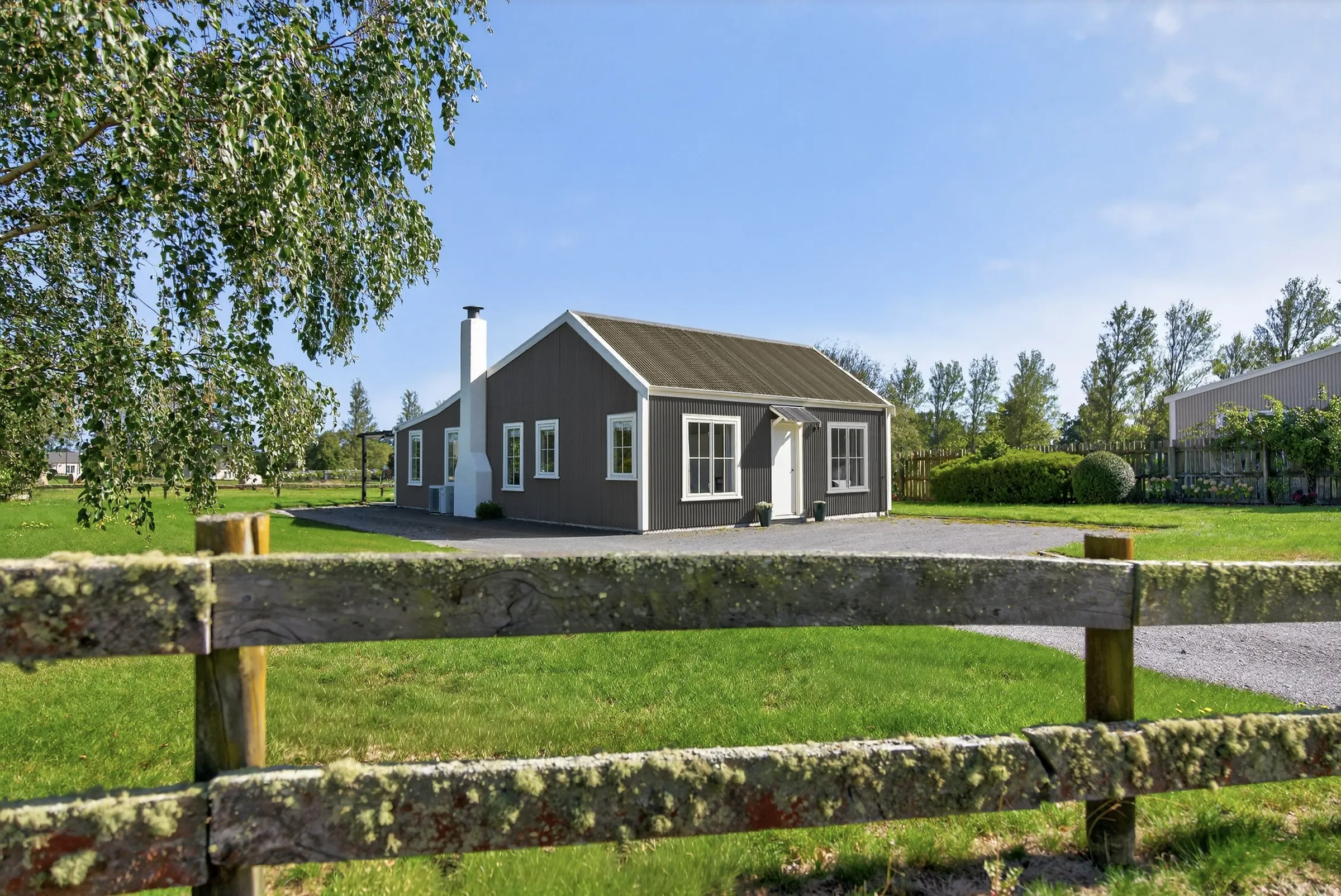 A standalone cottage behind a timber post and rail fence