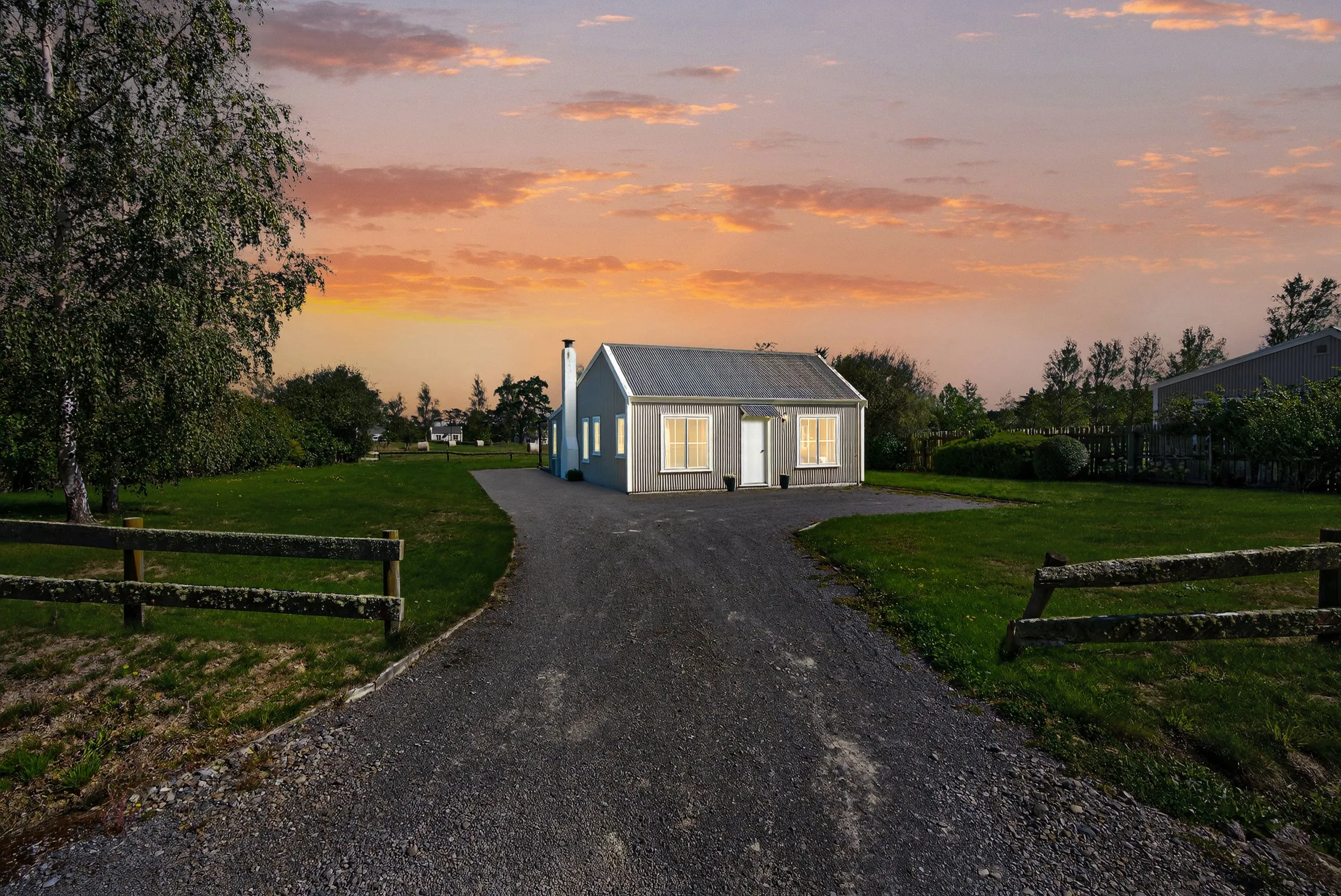 A cottage at dusk at the end of a long driveway