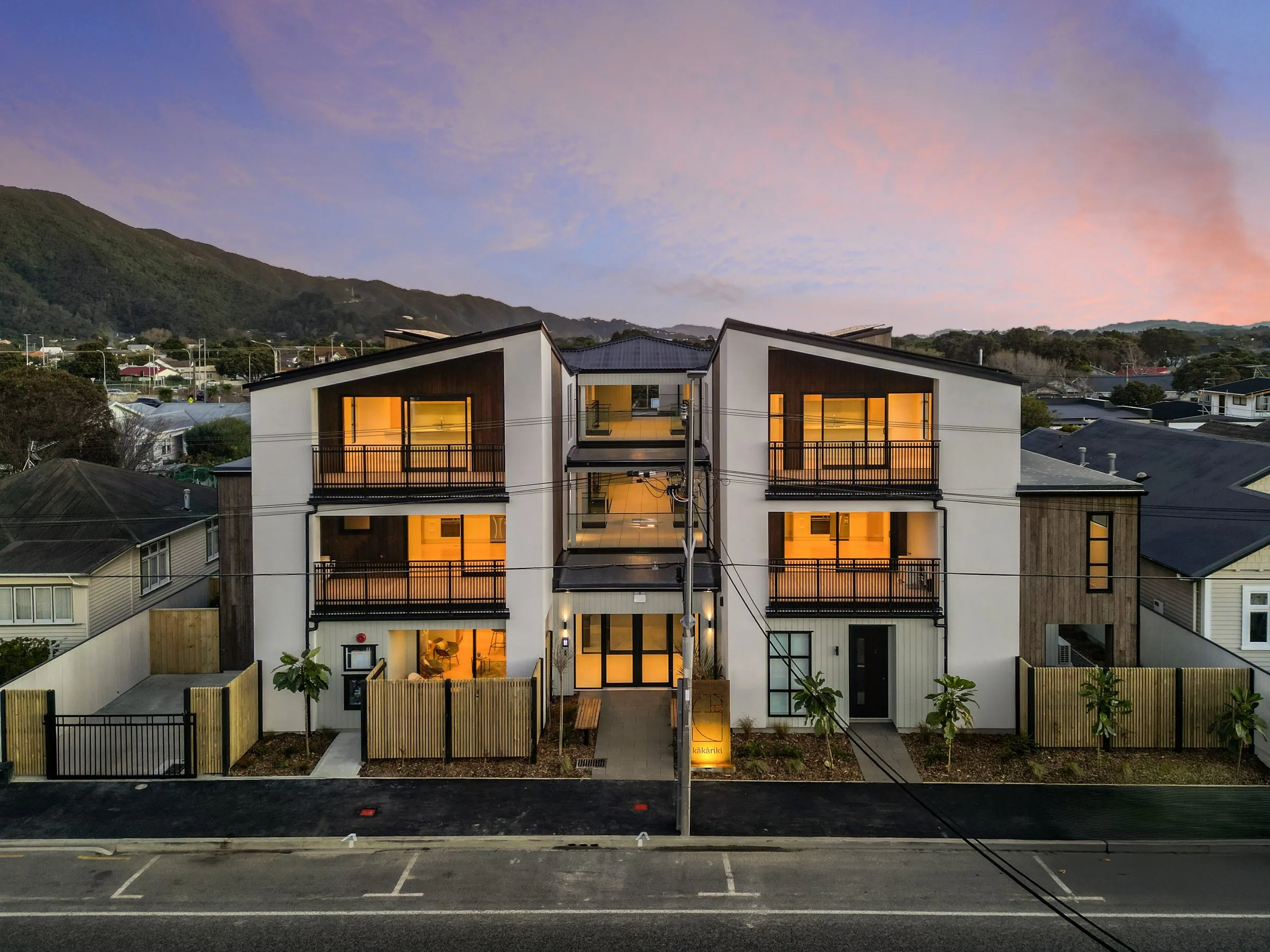 Kakariki at dusk, a three storey apartment building lit up against the Hutt hills